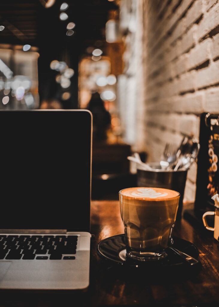 clear glass cup on black and silver laptop computer