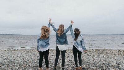 4 women standing on beach during daytime